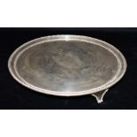 A SILVER SALVER with a central engraved crest and bearing the inscription to the reverse 'a