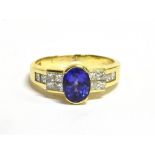 STAMPED 18K TANZANITE AND DIAMOND RING The ring set with a single oval cut Tanzanite with diamond