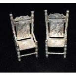 ANTIQUE PAIR OF MINIATURE SILVER CHAIRS Imitation rush seats with high backs embossed with figure