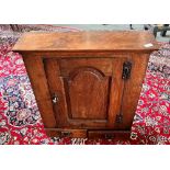 AN OAK HANGING CUPBOARD the door with arched fielded panel opening the three shelves, above pair