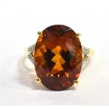 CITRINE AND DIAMOND RING IN 18CT GOLD A modern oval mixed cut citrine ring with grain set diamond
