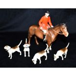 A BESWICK FIGURE OF A HUNTSMAN ON A BAY HORSE Height 21.5cm, with four Beswick figures of hounds (