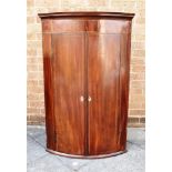 A GEORGE III MAHOGANY BOW FRONT HANGING CORNER CUPBOARD with parquetry inlaid decoration, two