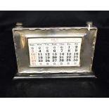 SILVER FRAMED PERPETUAL CALENDAR Stands 12.5cm high on a 21cm long wooden base, with ribbon scroll