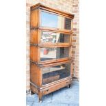 AN OAK FOUR TIER GLOBE WERNICKE SECTIONAL BOOKCASE with drawer to base, 87cm wide, the upper three