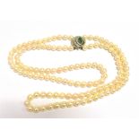 PEARL STRAND WITH DIAMOND & EMERALD A double strand of white cultured pearls, 43cm long, pearls