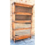 AN OAK FOUR TIER GLOBE WERNICKE STYLE SECTIONAL BOOKCASE with drawer to base, 87cm wide 31cm deep