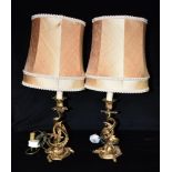 A PAIR OF GILT METAL ROCOCO STYLE TABLE LAMPS with shades, the bases 26cm high to top of sconce
