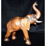 A LEATHER COVERED FIGURE OF AN ELEPHANT standing with trunk raised, 51cm high