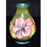 A MOORCROFT POTTERY VASE DECORATED IN THE 'HIBISCUS' PATTERN on a green ground, paper label to base,