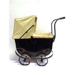A DOLL'S PRAM the metal body painted black with white lining and with a cream hood, on a sprung