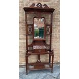 AN EDWARDIAN MAHOGANY HALLSTAND with central bevelled mirror surrounded by ten hooks, above marble