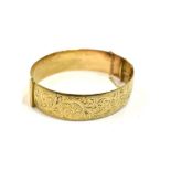 1940'S 9CT GOLD ENGRAVED BANGLE Oval profile, interior diameter 5.9cm, 16.0mm wide, with scroll