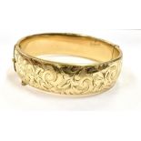 9CT ROLLED GOLD CUFF BANGLE 18.7mm wide, with scroll & foliate engraved front, hinge to one side and
