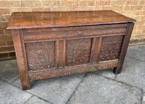 AN OAK RECTANGULAR COFFER with candle box, carved triple panel front and on stile feet, height 65cm,