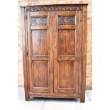 A DARK OAK PANELLED HANGING CUPBOARD the frieze carved with lunettes and on stile feet, height