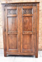 A DARK OAK PANELLED HANGING CUPBOARD the frieze carved with lunettes and on stile feet, height