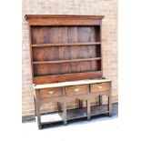AN OAK DRESSER the upper section with moulded cornice above three shelves, the base with three