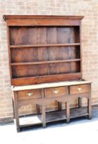 AN OAK DRESSER the upper section with moulded cornice above three shelves, the base with three