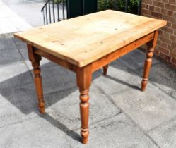 A RECTANGULAR PINE KITCHEN TABLE raised on four turned supports, 122cm x 72cm and height 79cm,