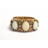 WHITE OPAL CABOCHON 9CT GOLD RING Three oval white opal cabochons alternating with single cut