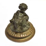 A LEAD FIGURE OF A BACCHANALIAN CHERUB on circular base with traces of gilding, 12cm high overall