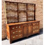 AN OAK DRESSER WITH LATER RACK the base with pair of fielded panelled doors flanked to each side