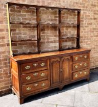 AN OAK DRESSER WITH LATER RACK the base with pair of fielded panelled doors flanked to each side