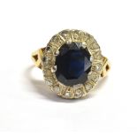 SAPPHIRE & DIAMOND HALO RING Dark blue oval mixed cut sapphire approx 10.7 x 7.0mm, surrounded by