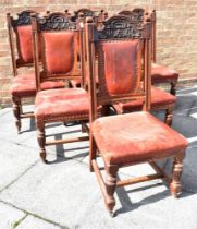 A SET OF SIX LATE VICTORIAN CARVED OAK DINING CHAIRS with red leather upholstered seats and backs,