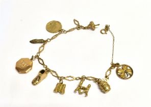 9CT GOLD CHARM BRACELET 22cm long with mostly 9ct gold charms attached, octagonal monogrammed locket