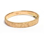 9CT ENGRAVED GOLD BANGLE 8.1mm wide scroll and foliate engraved front with plain rear, safety