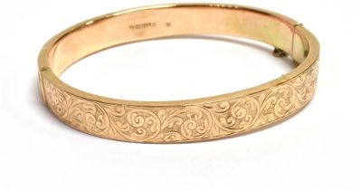 9CT ENGRAVED GOLD BANGLE 8.1mm wide scroll and foliate engraved front with plain rear, safety