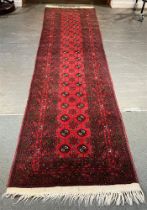 A CRIMSON GROUND RUNNER 20th century, 305cm long.