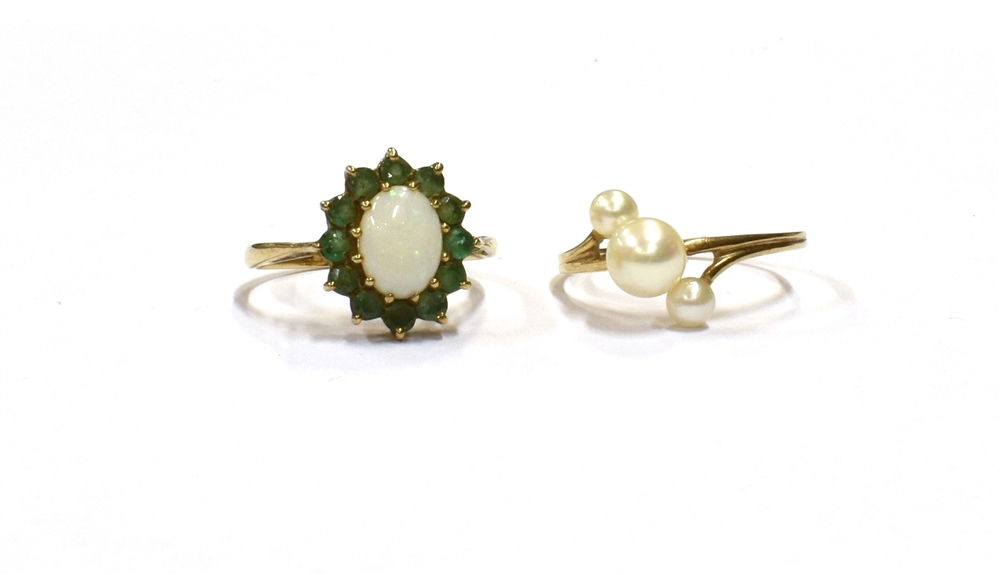 9CT GOLD GEM SET RINGS To include an oval solid white opal cabochon with a halo of round emeralds