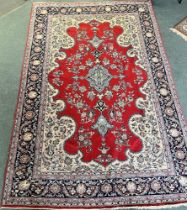 A PERSIAN KASHAN CARPET with a predominantly red ground, 295cm x 196cm.