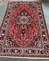 A PERSIAN KERMAN CARPET with a predominantly red ground, 310cm x 208cm.