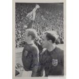 Bobby Moore signed b&w picture holding the Jules Rimet trophy aloft parading around Wembley Stadium