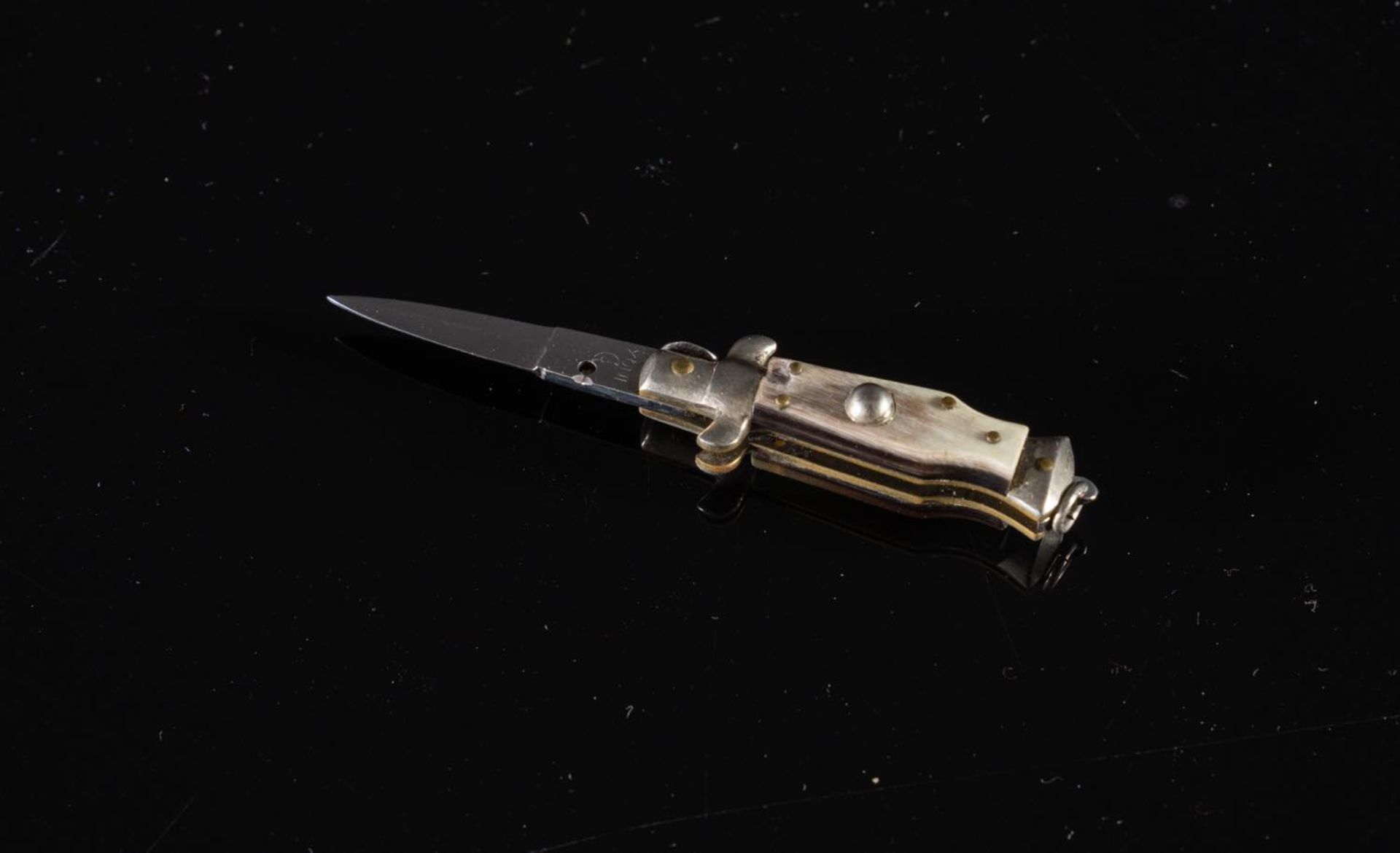Piccolo coltello a serramanico, XX secolo.Corpo in metallo con inserti del manico in corno, H max