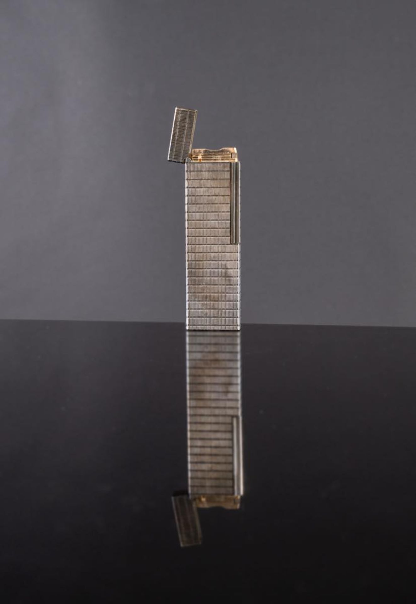 S. T. Dupont, Accendino da tavolo laminato in argento, Parigi, XX secolo.Reca alla base iscrizione