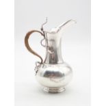 An Art Nouveau silver hot water jug, of swollen baluster form with a flaring rim, the woven handle
