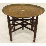 A 20th century circular Moorish style brass topped table on folding base (def), 48cm high x 57cm