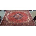 A red ground Kashan rug with dark blue central medallion, white spandrels and a multicoloured flower