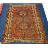 A terracotta ground tribal Balouche rug with pair of geometric medallions and multicoloured borders,