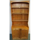 A 20th century pine open bookcase with three open shelves over pair of cabinet doors, 183cm high x