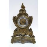 A French gilt metal clock of rococo style, the dial with white and blue enamel roman numeral