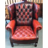 A 20th century red leather button back upholstered Chesterfield style wing back armchair, 109cm high