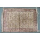 A CREAM GROUND SILK AND WOOL PERSIAN RUG with floral foliate all-over design and pink borders, 185cm