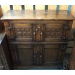 A 20th century oak side cabinet with pair of carved cabinet doors over pair of panel doors on