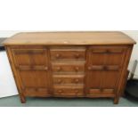 A 20th century elm and beech Ercol golden dawn sideboard with four central drawers flanked by